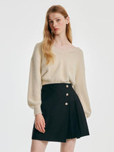 A lady wears a sweater and skort.